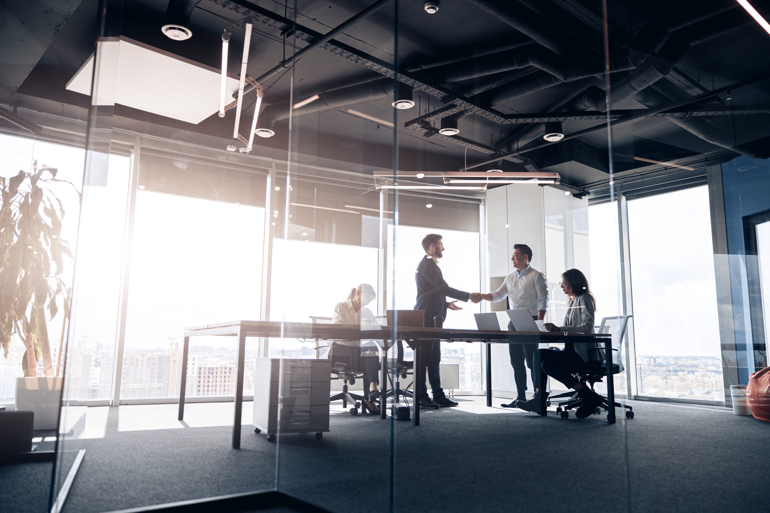 People standing near table, team of young businessmen working and communicating together in office